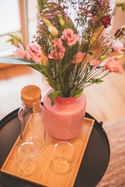 Blumen in einer Vase. Wassergläser auf einem Tablett.